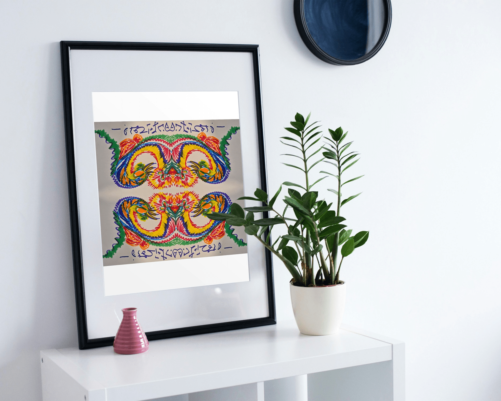 Framed abstract art and a potted plant on a white table.