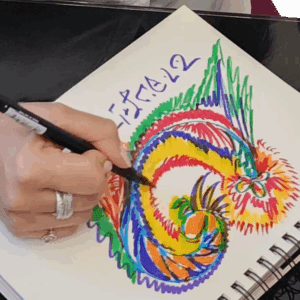 A person drawing a colorful dragon in a sketchbook.